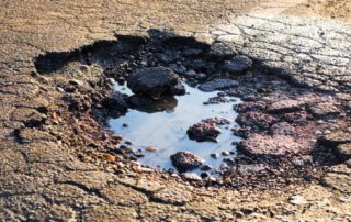 A pothole that cause damage to vehicles.